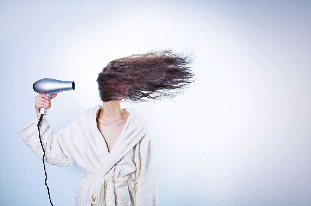 mujer joven con un secador, secandose el pelo